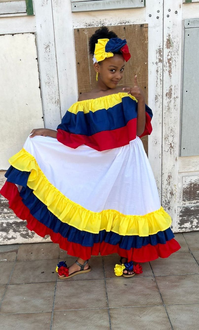 Girl in traditional Curaçao dress by a blue door