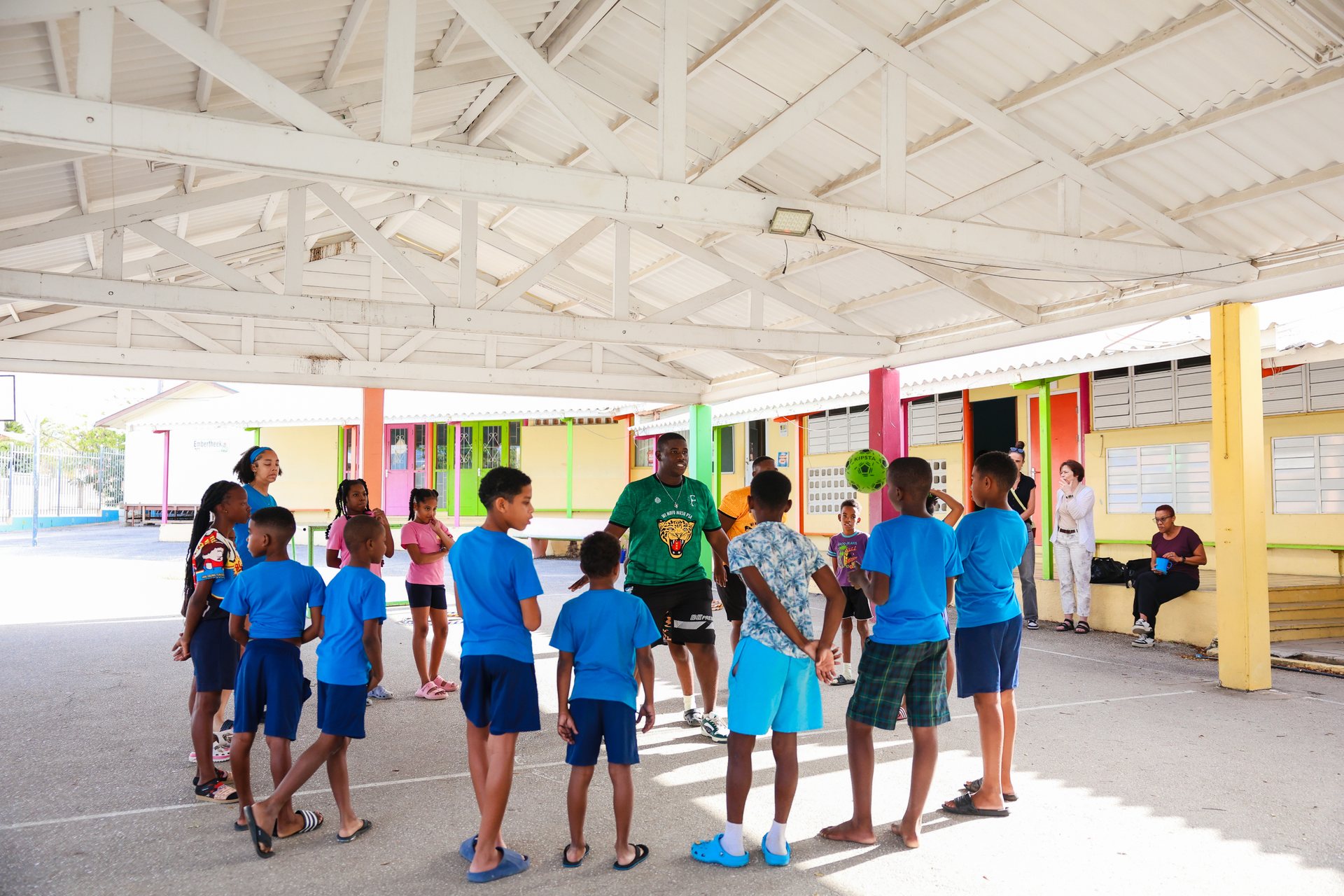 Schoolchildren in blue uniforms standing in rows under the canopy of the schoolyard