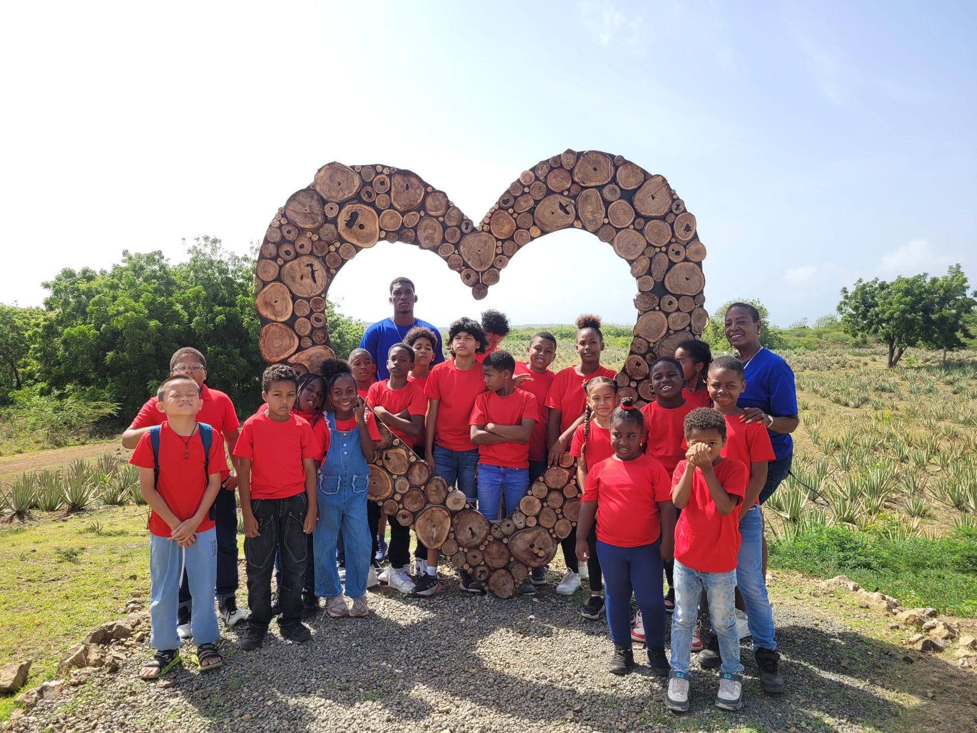 Schoolchildren posing at a heart shaped monument during an outdoor activity