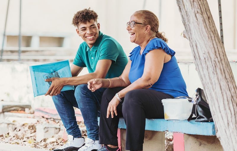 Two young people talking on a low wall outside
