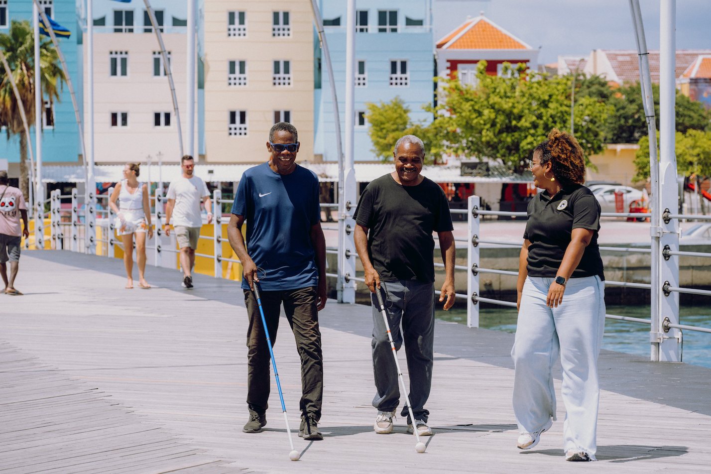 Passers by on the Handelskade in Willemstad, among them someone on crutches